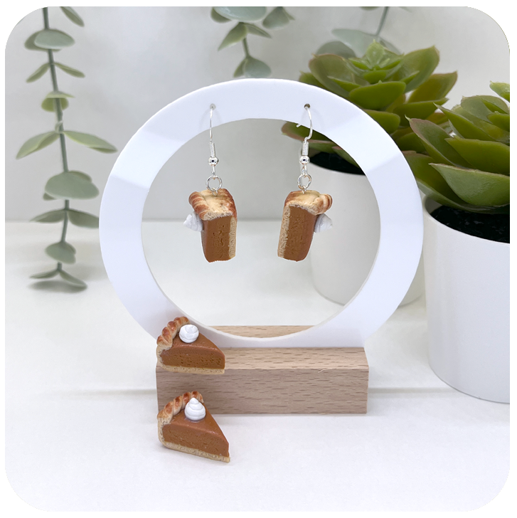 polymer clay pumpkin pie slice earrings with whipped cream detail and sterling silver hooks.